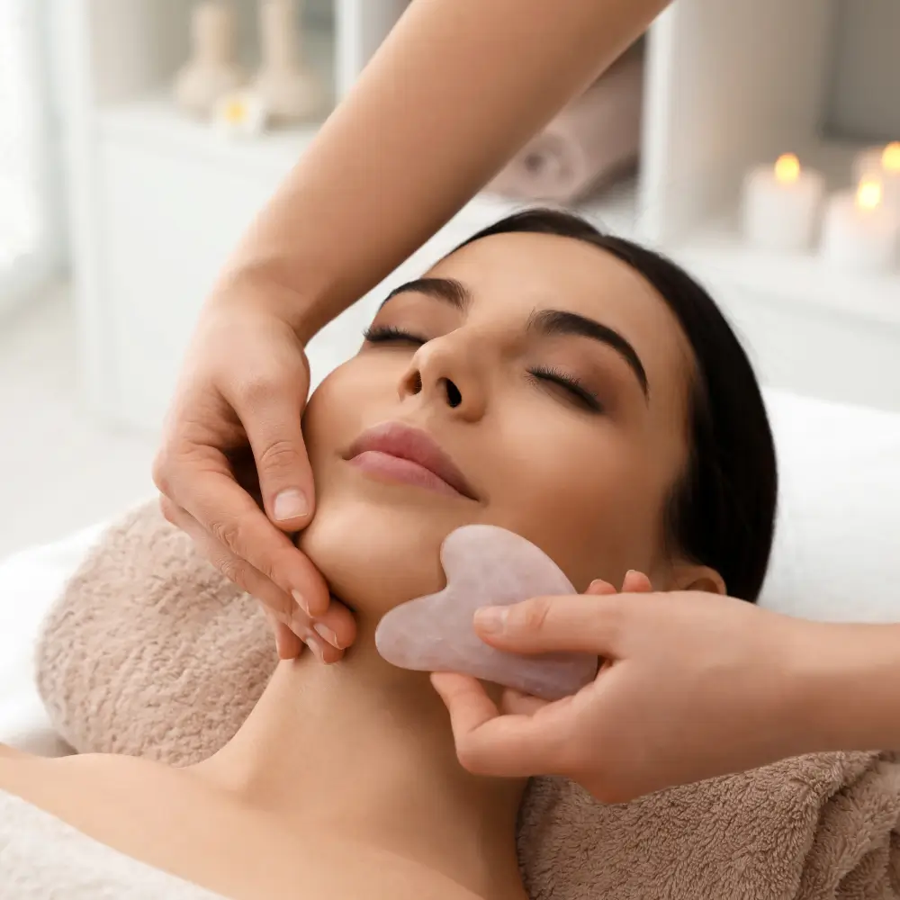 Alona using gua sha on client’s jawline, sculpting treatment